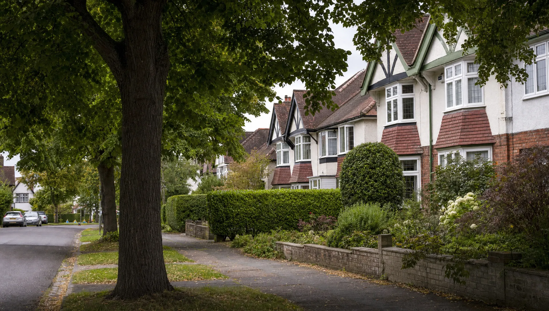 A quiet Ickenham street with mature trees, 1930s semis, clipped hedges and well-kept front gardens.